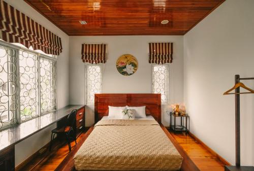 ein Schlafzimmer mit einem Bett in einem Zimmer mit Fenstern in der Unterkunft Le Robinet Villa - a journey into Hue citadel soul in Hue
