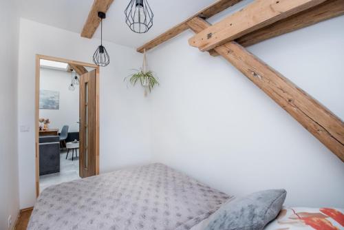 sypialnia z łóżkiem i drewnianymi belkami stropowymi w obiekcie Apartament Mikołowska w mieście Gliwice