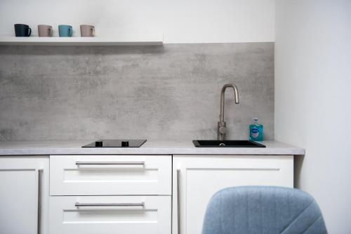 a kitchen with a sink and a blue chair at Apartament Mikołowska in Gliwice
