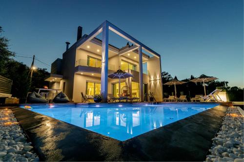 een villa met een zwembad in de nacht bij White Pearl Premium Villa Corfu in Evropoúloi