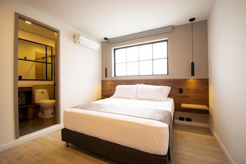 a bedroom with a large bed and a bathroom at HOTEL FENCE in Medellín
