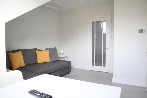 Twelve Thirty Serviced Apartments - 1 Croydon في South Norwood: غرفة معيشة مع أريكة رمادية ووسائد صفراء