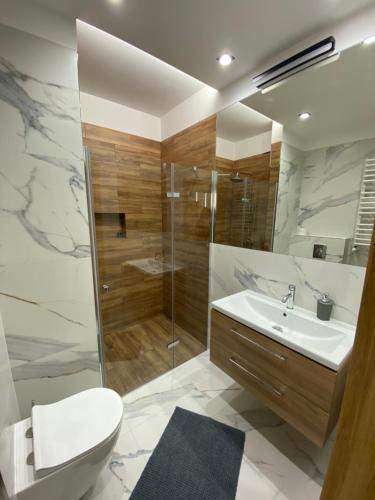a bathroom with a shower and a toilet and a sink at Apartamenty Białe nad jeziorem Białym in Augustów