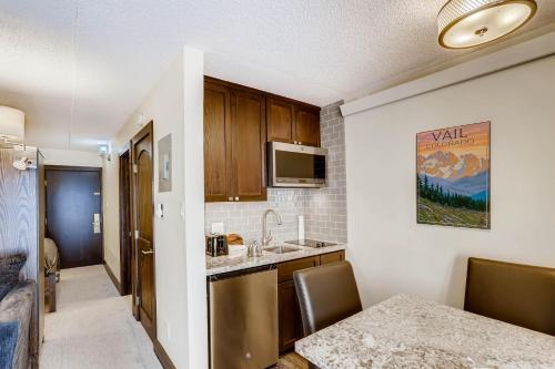 a kitchen with a sink and a table with chairs at Lifthouse Lodge - Premium Studio in Vail