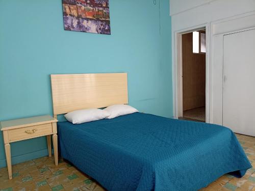 Dormitorio azul con cama y mesita de noche en Hotel San Carlos, en Irapuato