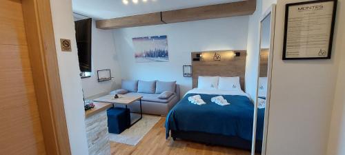 a bedroom with a blue bed and a couch at Apartmani MONTES Jahorina in Jahorina