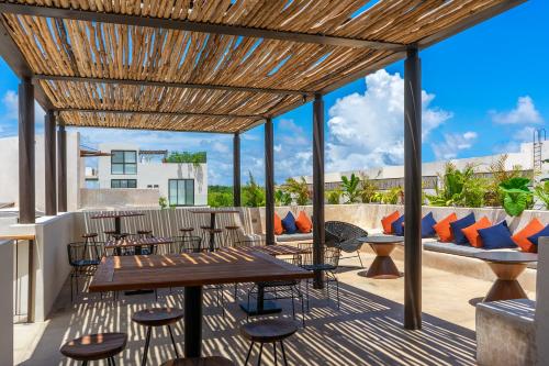 un patio con tavoli, sedie e pergolato in legno di Private pool and rooftop for 3 a Tulum
