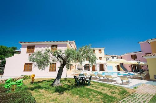 a house with a tree and chairs and a pool at Residence con piscina a Sos Alinos in Cala Liberotto