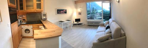 Una sala de estar con un sofá y una cocina. en studio residence Grands Montets, en Chamonix-Mont-Blanc