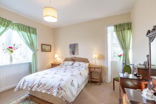 a bedroom with a large bed and two windows at Chapelton Cottage No 2 in Kirkcudbright