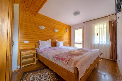Un dormitorio con una cama con paredes de madera y una ventana en Cabana TYF Dreptu - TYFTRAVEL SRL, en Poiana Teiului