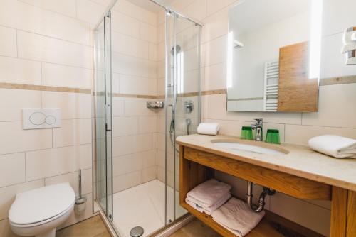 uma casa de banho com um chuveiro, um lavatório e um WC. em Haus Sabrina - Ferienwohnungen em Saalbach Hinterglemm
