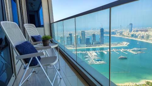 a balcony with two chairs and a view of the harbor at Exquisite, luxe 1BD Apartment, Unparalleled Sea Views, Prime Dubai Marina Location & Full Kitchen by "La Buena Vida Holiday Homes in Dubai