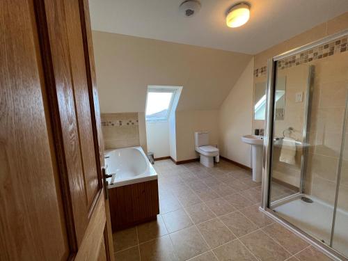 a bathroom with a tub and a shower and a toilet at Airigh nam Fiadh in Clachan