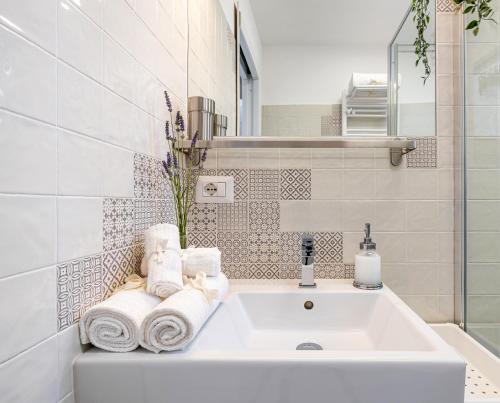 a white bathroom with a sink and towels at PIGNETO VILLAGE Roma Guest House Apartment in Rome