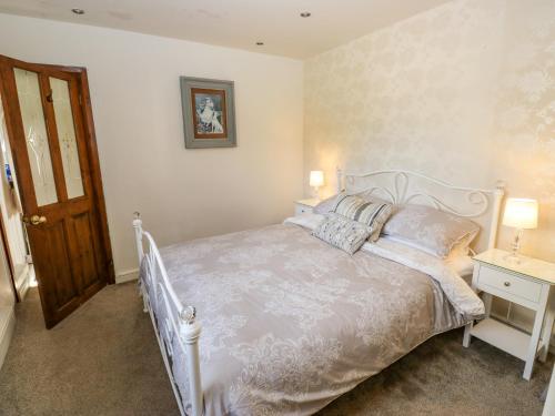 a bedroom with a white bed with pillows and a door at Prospect Cottage in Sowerby Bridge