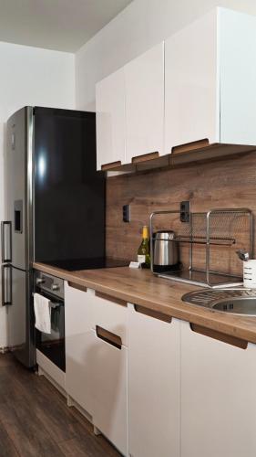 a kitchen with white cabinets and a black refrigerator at U Šípků in Ostrava