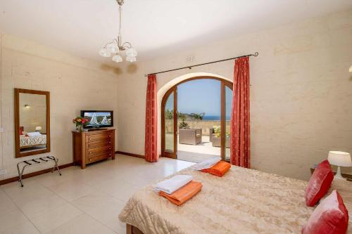 1 dormitorio con 1 cama, TV y ventana en The Olives Holiday Home, en San Lawrenz