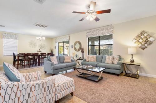 een woonkamer met 2 banken en een plafondventilator bij Moonlight Ridge - 5 bed ChampionsGate Resort pool home in Davenport