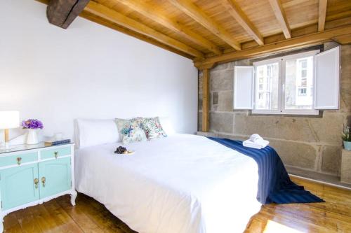 a bedroom with a white bed and a window at Vella Nova by Serendipia Turismo in Santiago de Compostela