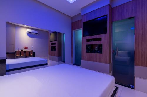 une chambre avec un lit blanc et une télévision dans l'établissement Sfera Motel, à Manaus