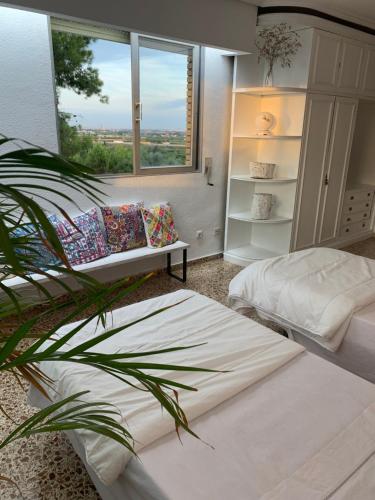 een slaapkamer met 2 bedden en een raam en een plant bij Villa Entrenaranjos in Picassent