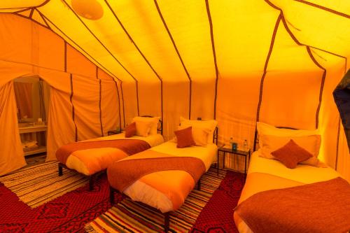 a room with three beds in a tent at Luxury Bega Camp in Merzouga