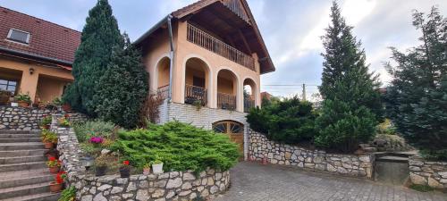 a house with a stone wall and trees and plants at Eszter-lak in Monostorapáti
