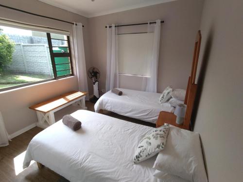 two beds in a room with a window at 2 Bedroom Guest Suite at A-frame Glengariff Beach in Glen Eden