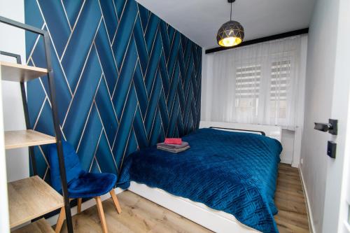 a bedroom with a blue accent wall and a bed at Apartament w Centrum in Iława