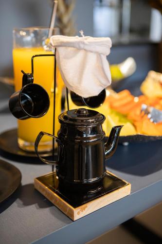 a tea kettle on a table with a plate of food at Hotel Darolt Criciúma in Criciúma