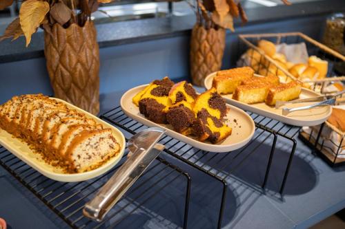 a table with three plates of cake and bread at Hotel Darolt Criciúma in Criciúma