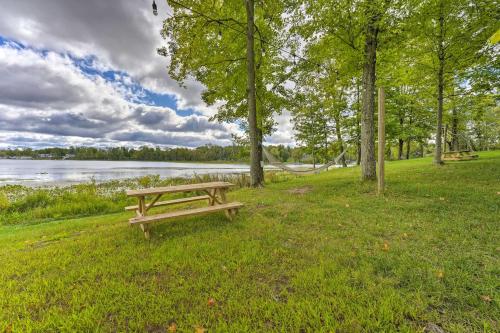 a wooden bench sitting in the grass next to a lake at Pet-Friendly Cassopolis Escape with Lake Access in Cassopolis