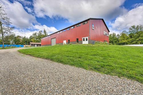 a red barn on a grassy hill next to a road at Cassopolis Cabin, Private Deck and Lake Access! in Cassopolis