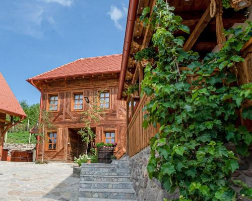 a log house with a ivy growing up the side of it at Székelyföld,Siklódi Kő Vendégház Szénatároló in Bartoştana