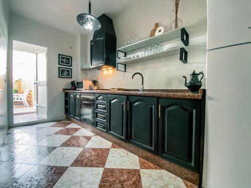 a kitchen with black cabinets and a checkered floor at APARTAMENTOS FERNANDO III EL SANTO in Baeza