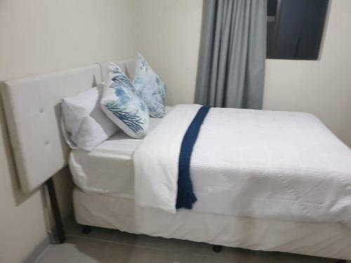 a white bed with blue and white pillows on it at No 12 Tugela Mouth in Tugela Mouth