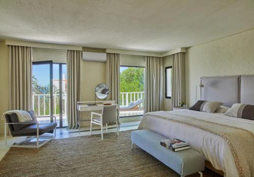 een slaapkamer met een bed, een bureau en een balkon bij Posada Tamarindo in José Ignacio