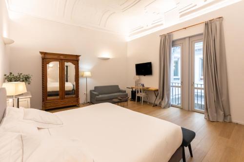 a white bedroom with a bed and a chair at Hospedium Hotel Posada de la Silleria in Toledo