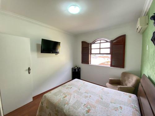 a bedroom with a bed and a window and a television at Elite Palace Hotel in Pará de Minas