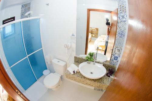 a bathroom with a sink and a toilet and a mirror at Pousada Paraíso Tropical in Penha