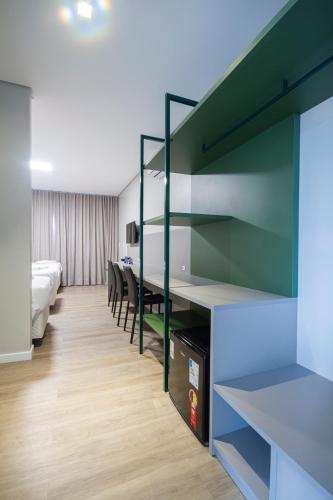 a bedroom with a bed and a desk in a room at Hotel Darolt Criciúma in Criciúma