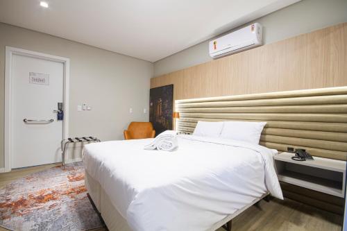 a bedroom with a large white bed in a room at Hotel Darolt Criciúma in Criciúma