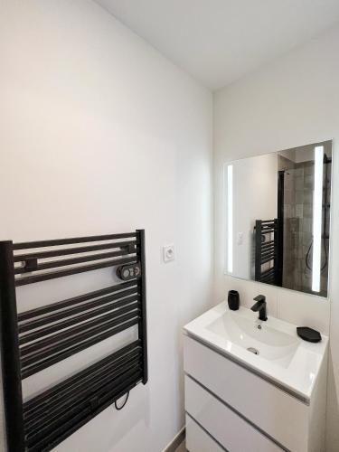 une salle de bain blanche avec un lavabo et un miroir dans l'établissement Le Cobalt - Hypercentre - Gare - Netflix, à Toulouse
