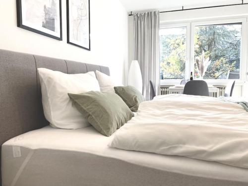 Una cama con sábanas blancas y almohadas en un dormitorio en Top-Apartment mit Parkplatz und Balkon, en Reutlingen