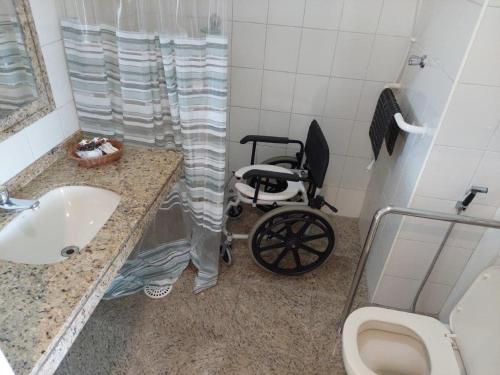 a wheelchair in a bathroom with a sink and a toilet at Hotel Aojesp in Caraguatatuba