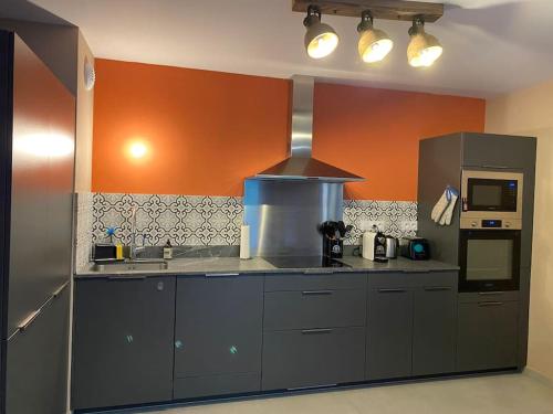 - une cuisine avec un mur orange et une cuisinière dans l'établissement Gorgeous 2 bedroom, 2 full bath, ski in apartment! Winner of 2025 and 2024 Traveller Award!, à Morzine