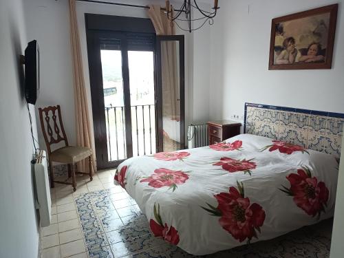 Un dormitorio con una cama con flores rojas. en El Corralon de Severo, en Hinojales