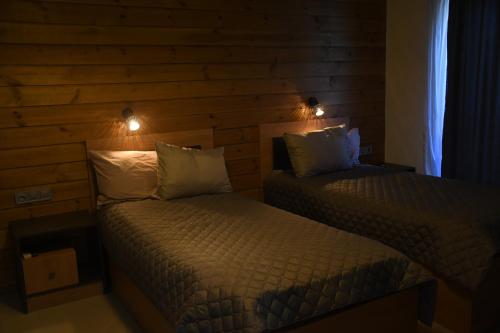 2 aparte bedden in een kamer met houten wanden bij Къща за гости Авена in Banya