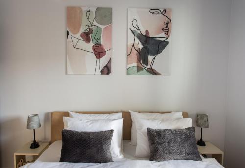 a bedroom with a bed with two paintings on the wall at LINA - PG, Riverside Apartment in Podgorica